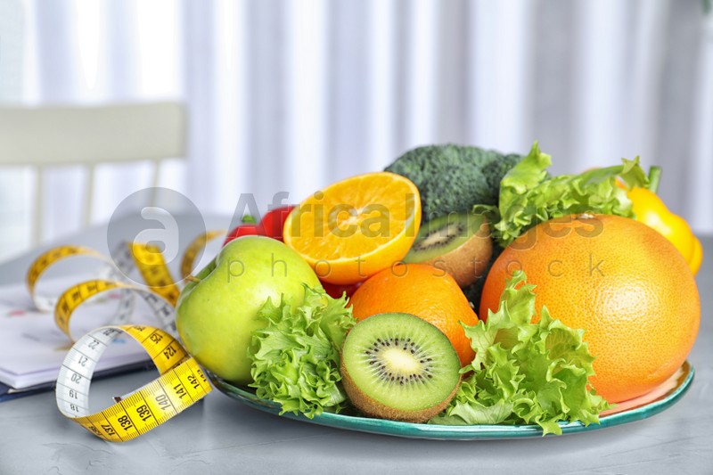 Measuring tape, vegetables and fruits on table. Diet plan from nutritionist