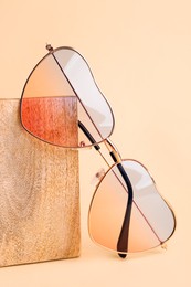 Stylish elegant heart shaped sunglasses on beige background