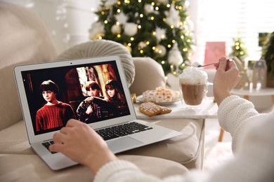 Photo of MYKOLAIV, UKRAINE - DECEMBER 25, 2020: Woman watching Harry Potter movie on laptop at home, closeup. Cozy winter holidays atmosphere