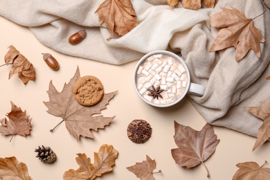 Flat lay composition with hot cozy drink and autumn leaves on color background