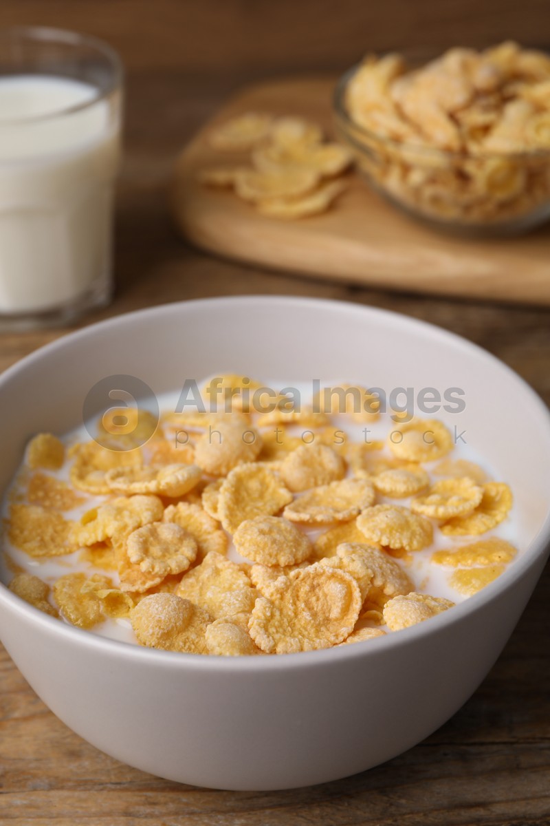 Tasty cornflakes with milk in bowl on wooden table, closeup
