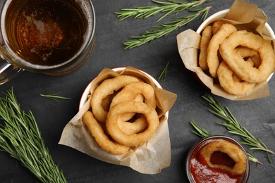 Fried onion rings served on black table, flat lay