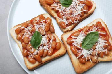 Toasts with delicious canned beans on light grey table, top view