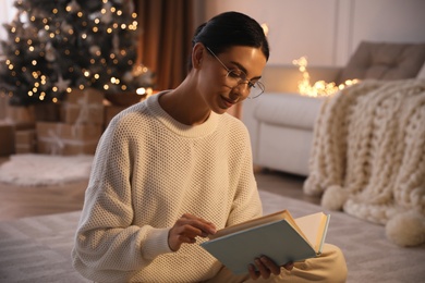 Young woman reading book at home. Christmas celebration
