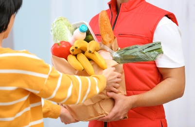 Male courier delivering food to client on light background, closeup