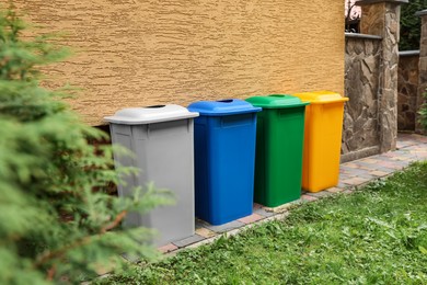 Photo of Many colorful recycling bins near yellow wall outdoors
