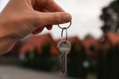 Photo of Real estate agent holding keys to new house outdoors, closeup