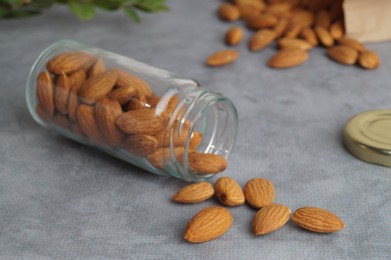 Photo of Jar with delicious almonds on grey table