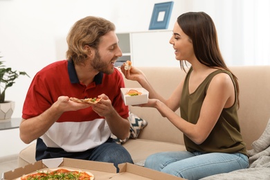 Young couple having lunch in living room. Food delivery
