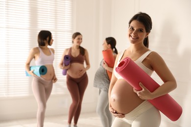 Group of pregnant women with mats in yoga class, space for text