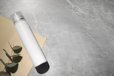 Dry shampoo spray and eucalyptus on light grey marble table, flat lay. Space for text