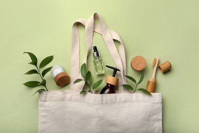 Bag with eco friendly products on green background, flat lay