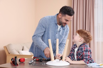 Father teaching son how to make stool at home. Repair work