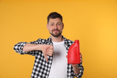 Man holding red container of motor oil and showing thumbs down on orange background