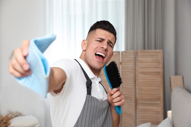 Man with brush and rag singing while cleaning at home