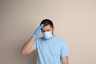 Stressed man in protective mask on beige background. Mental health problems during COVID-19 pandemic