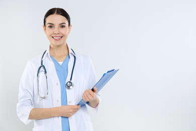 Portrait of young doctor with stethoscope and clipboard on white background