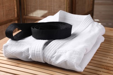 Martial arts uniform with black belt on table indoors
