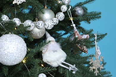 Beautiful Christmas tree with decor on light blue background, closeup