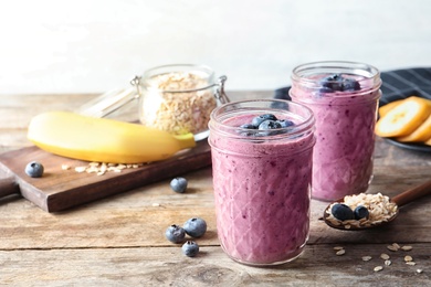Jars with blueberry smoothies on wooden table