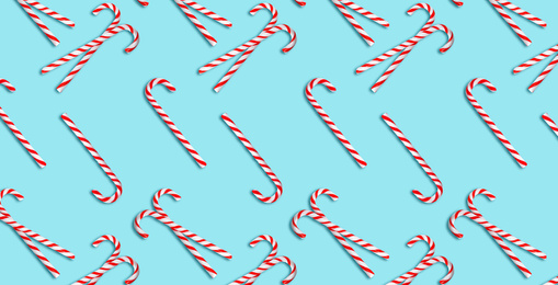 Pattern of Christmas candy canes on pale light blue background, top view. Banner design