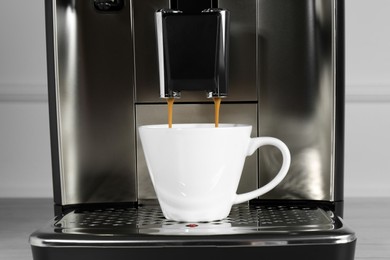 Espresso machine pouring coffee into cup on drip tray, closeup