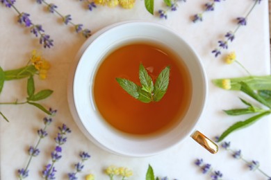Photo of Tasty herbal tea and flowers on white table, flat lay