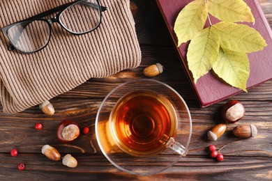 Flat lay composition with cup of aromatic tea and soft sweater on wooden table. Autumn atmosphere