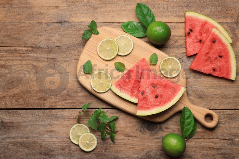 Tasty sliced watermelon and limes on wooden table, flat lay