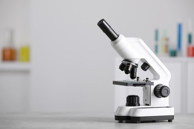 Modern medical microscope on grey table in laboratory, space for text