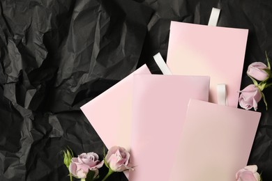 Scented sachets and roses on black crumpled paper, flat lay. Space for text