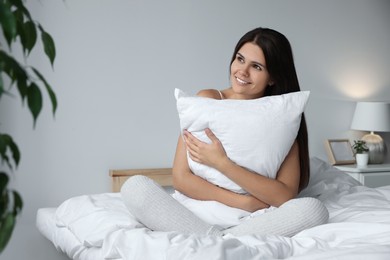 Photo of Beautiful young woman hugging pillow on bed at home