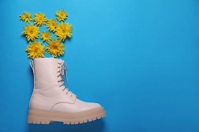 Photo of Stylish leather shoe with flowers on light blue background, flat lay. Space for text