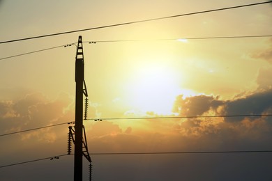 Silhouette of telephone pole with cables on sunny day