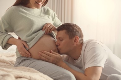 Photo of Young pregnant woman with her husband in bedroom, closeup
