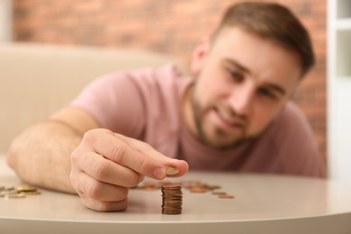 Young man with coins at home, closeup. Saving money