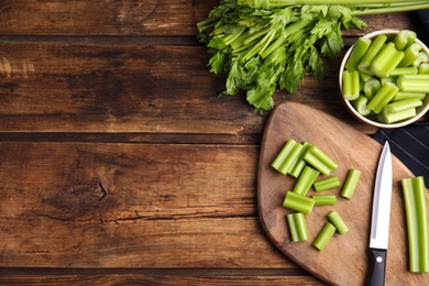 Photo of Fresh ripe green celery on wooden table, flat lay. Space for text