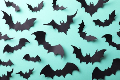 Many black paper bats on light blue background, flat lay. Halloween decor