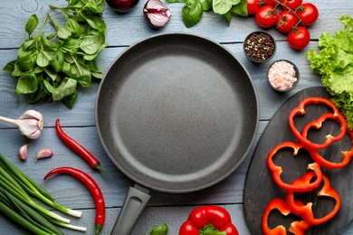 Flat lay composition with frying pan and fresh products on grey wooden table