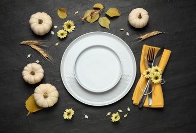 Festive table setting with pumpkins and flowers on black background, flat lay. Thanksgiving Day celebration