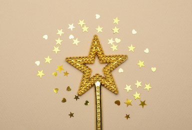 Beautiful golden magic wand and confetti on beige background, flat lay