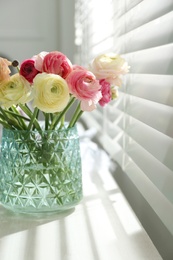 Beautiful ranunculus flowers in vase on window sill indoors