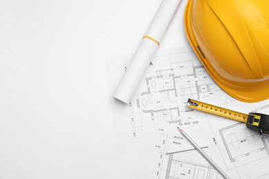 Photo of Flat lay composition with blueprints and hardhat on white background. Space for text