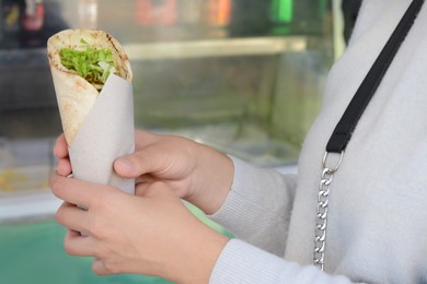 Photo of Woman holding delicious vegetable roll outdoors, closeup