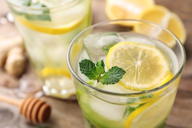 Glass of refreshing drink with lemon and mint on wooden table, closeup view. Space for text