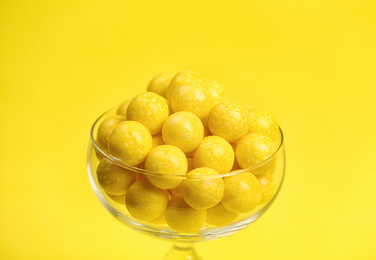 Tasty lemon chewing gums in glass on yellow background