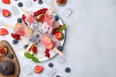 Photo of Flat lay composition with fruit and berry ice pops on light table. Space for text