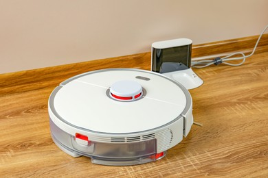 Robotic vacuum cleaner and charger on wooden floor indoors