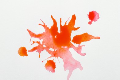 Photo of Orange ink blots on white canvas, top view
