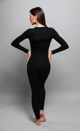 Woman wearing thermal underwear on grey background, back view